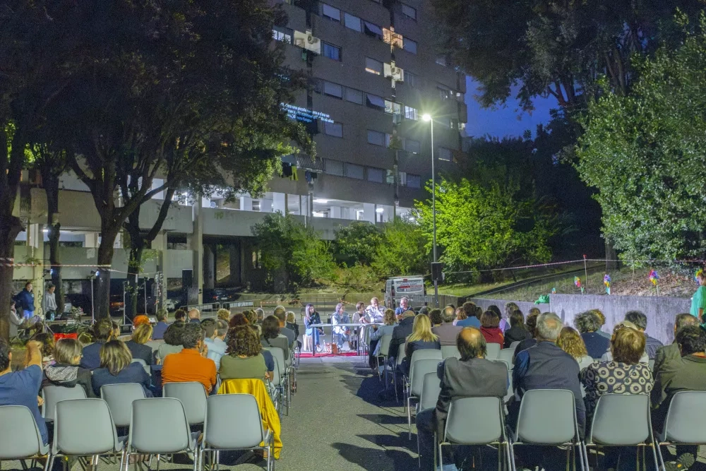 sitting audience and speakers at an evening's panel discussion in the courtyard