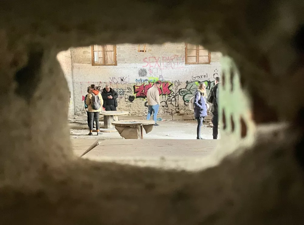 A glimpse through a hole in the wall of the abandoned railway building in Kozani, offering a peek into its graffiti-covered interior – soon to be revitalized as part of a new innovation hub.