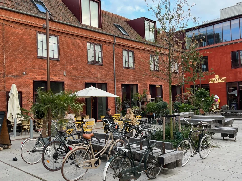 red bricks building with people sitting at outside tables and bicycles parked