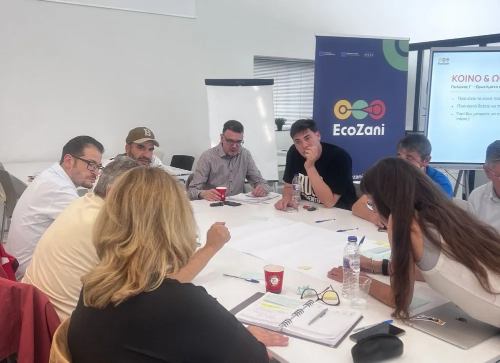 Participants take part in a discussion during an EcoZani workshop, sitting around a table with notes and documents, exchanging ideas in a collaborative working session.
